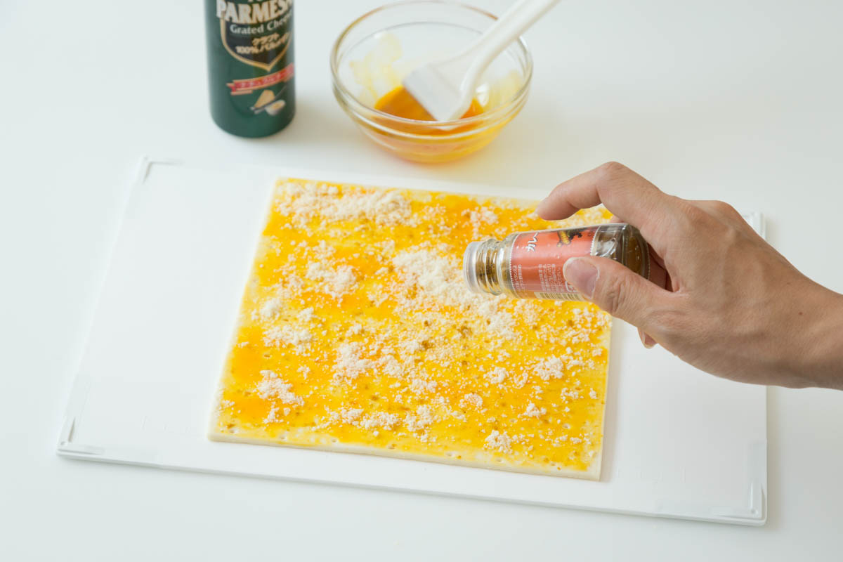 冷凍パイシートに粉チーズとカレー粉をふる