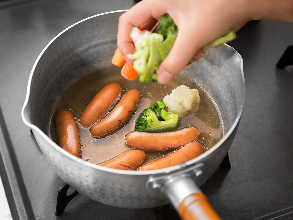 鍋の材料が沸騰したら、凍ったままの冷凍野菜ミックスを加える。