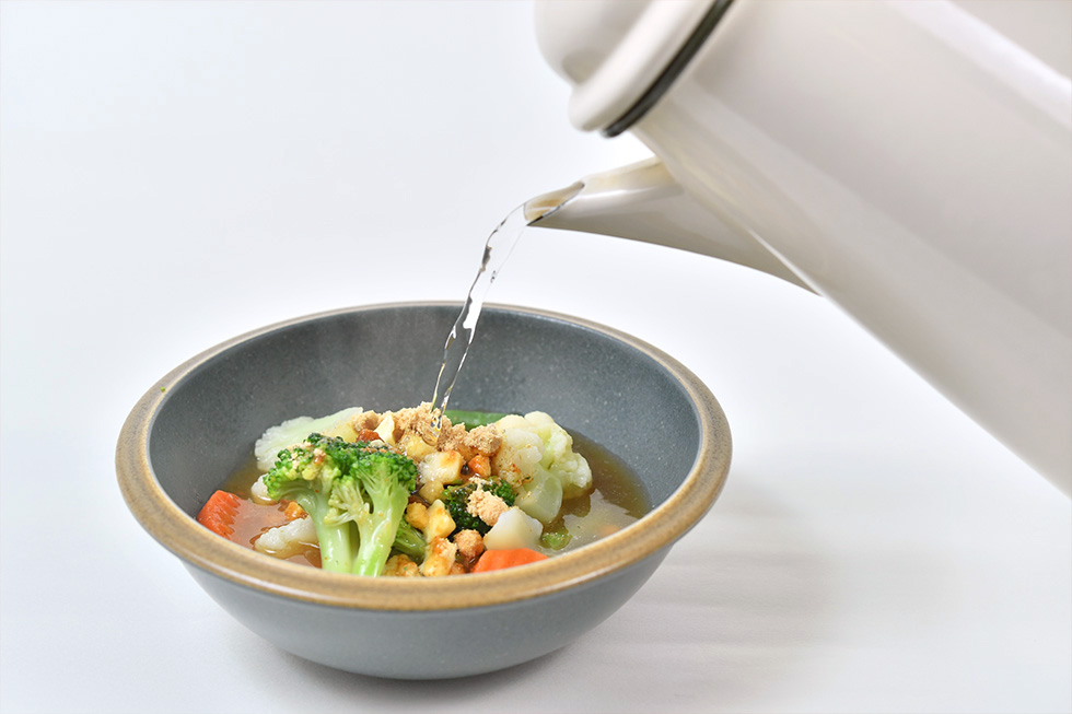 加熱した冷凍洋野菜ミックスの上にカップスープの粉末をかけ、その上からお湯を注ぐ。