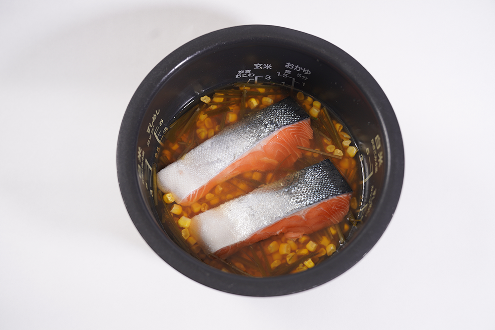 米の上に冷凍コーン、生鮭を乗せて炊飯器で炊く。